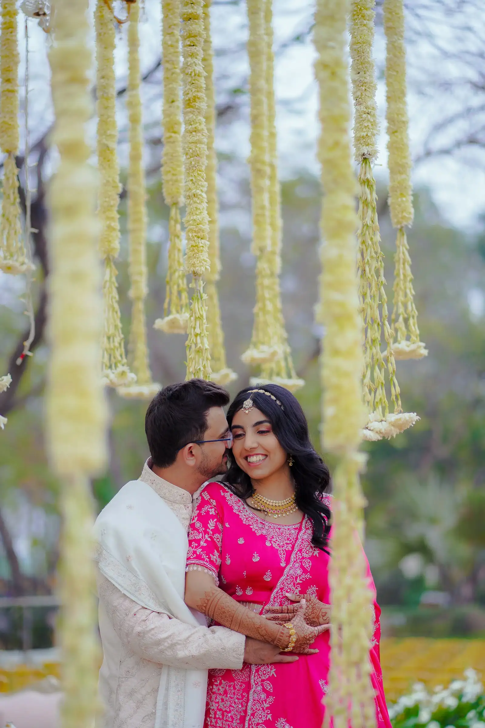 The couple embracing beneath a floral canopy